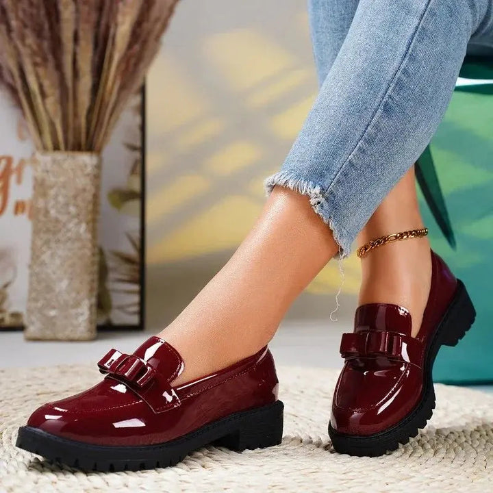 Slip-on women's comfort loafers with a glossy patent finish, elegant bow, and supportive orthopedic design.