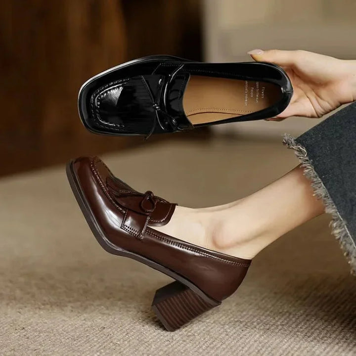 Detailed view of the stylish tassels & round toe on a women's elegant block heel loafer pump in black.