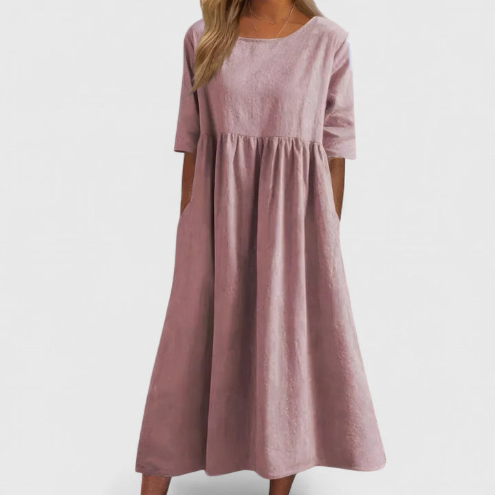 Women's flowy maxi dress featuring pockets, round neck, cinched waist. Elegant & lightweight.