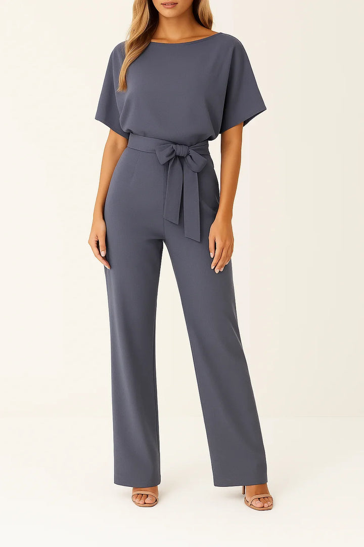 Model wearing a stylish women's short sleeve wide leg jumpsuit with a cinching tie waist. Summer fashion.