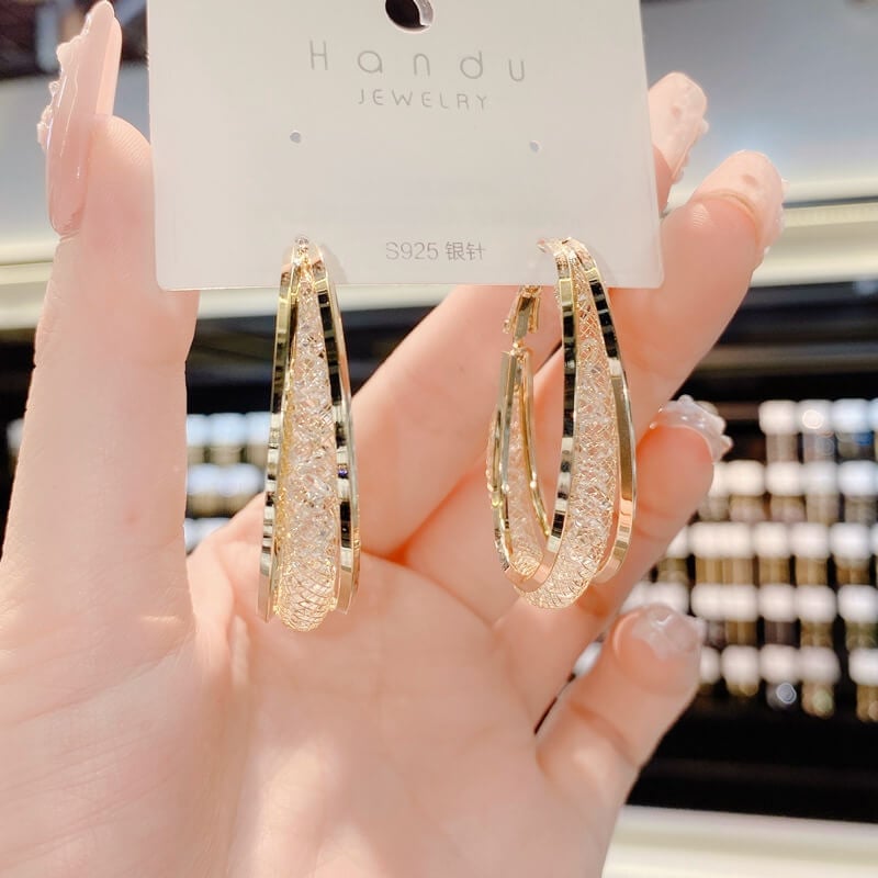 Fashionable women's twisted oval crystal hoop earrings, a sparkling and elegant jewelry piece.