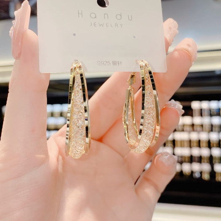 Fashionable women's twisted oval crystal hoop earrings, a sparkling and elegant jewelry piece.