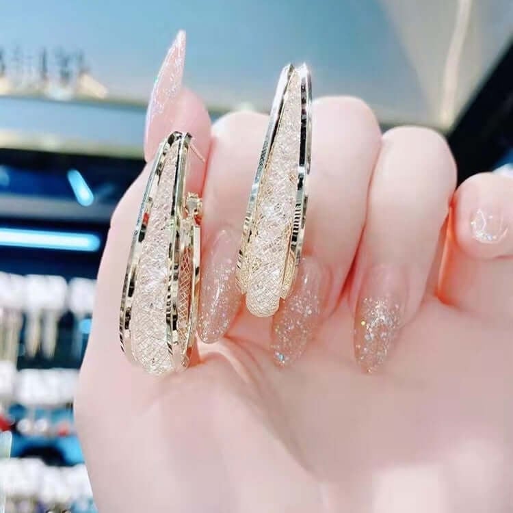 Dazzling women's twisted oval hoop earrings with brilliant crystals, enhancing any outfit.