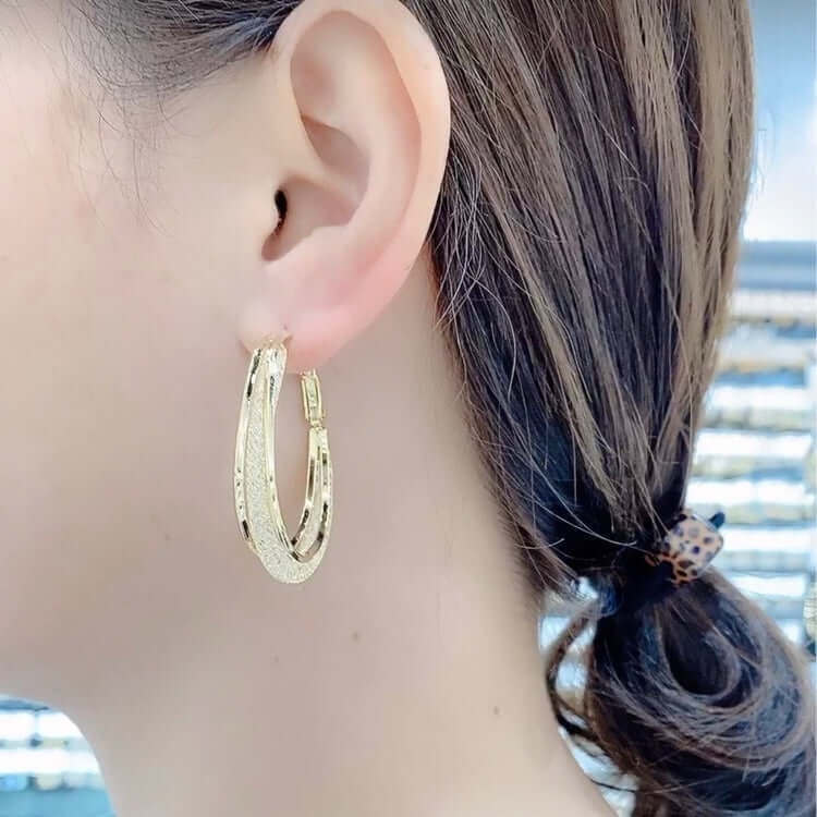 Chic women's twisted oval hoop earrings featuring sparkling crystals, an elegant jewelry accessory.