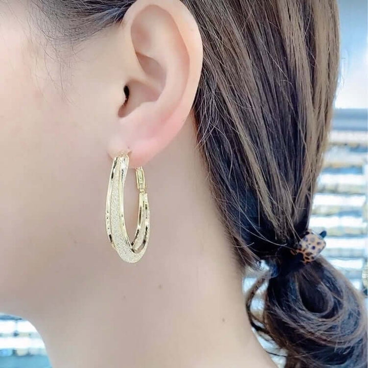 Chic women's twisted oval hoop earrings featuring sparkling crystals, an elegant jewelry accessory.