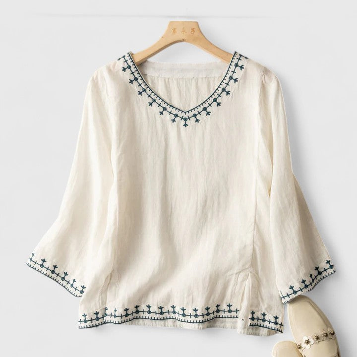 Stylish women's V-neck blouse with delicate embroidery. Comfortable short-sleeve top, perfect for casual chic or elegant wear.