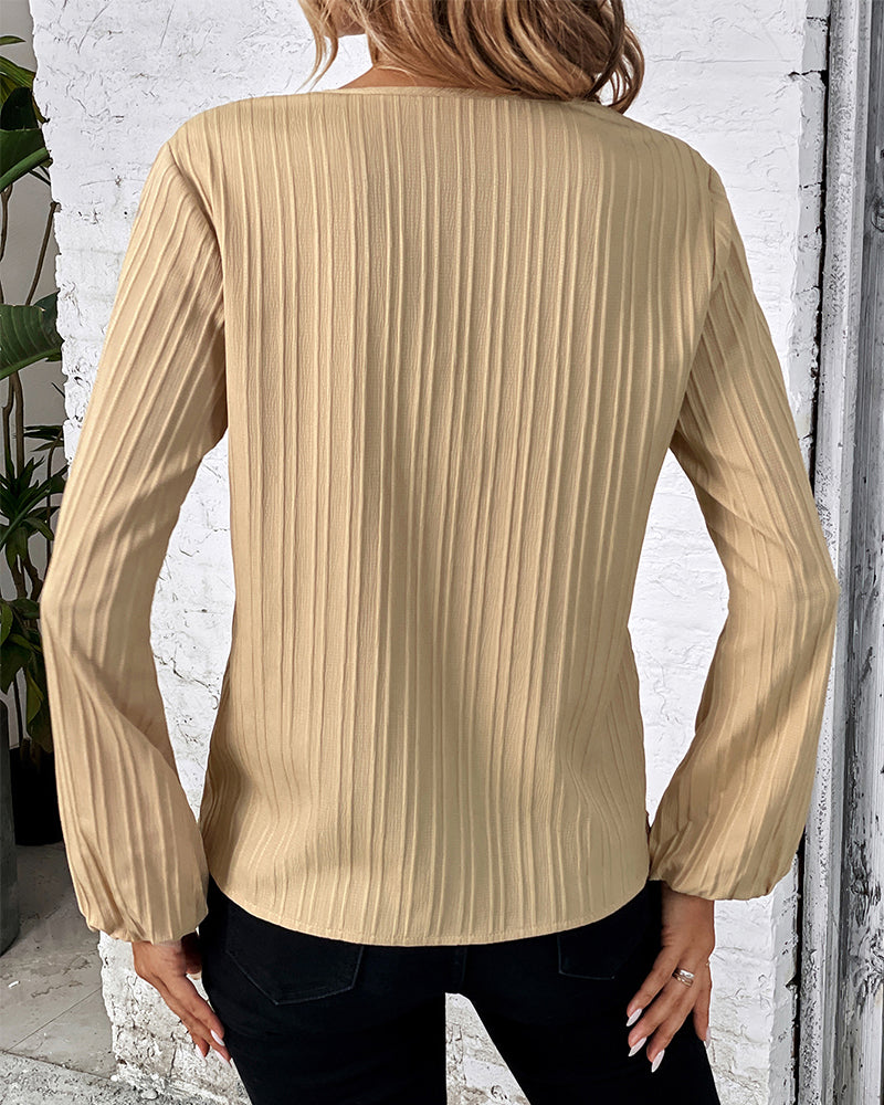 Trendy women's V-neck top featuring dramatic balloon sleeves. Stylish long sleeve blouse for elegant fashion.