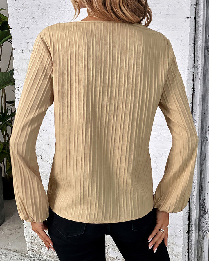 Trendy women's V-neck top featuring dramatic balloon sleeves. Stylish long sleeve blouse for elegant fashion.
