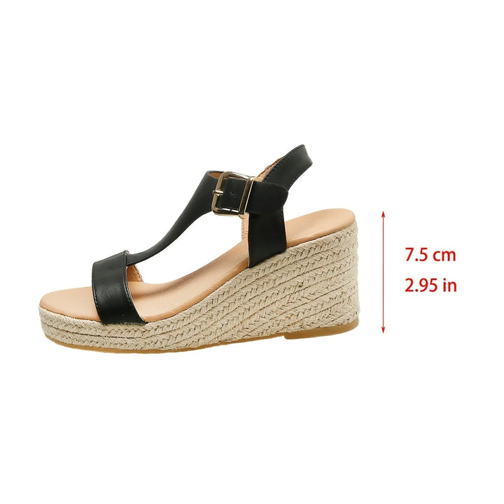 Feet wearing elegant women's T-strap espadrille wedge sandals with buckle closure, summer fashion.
