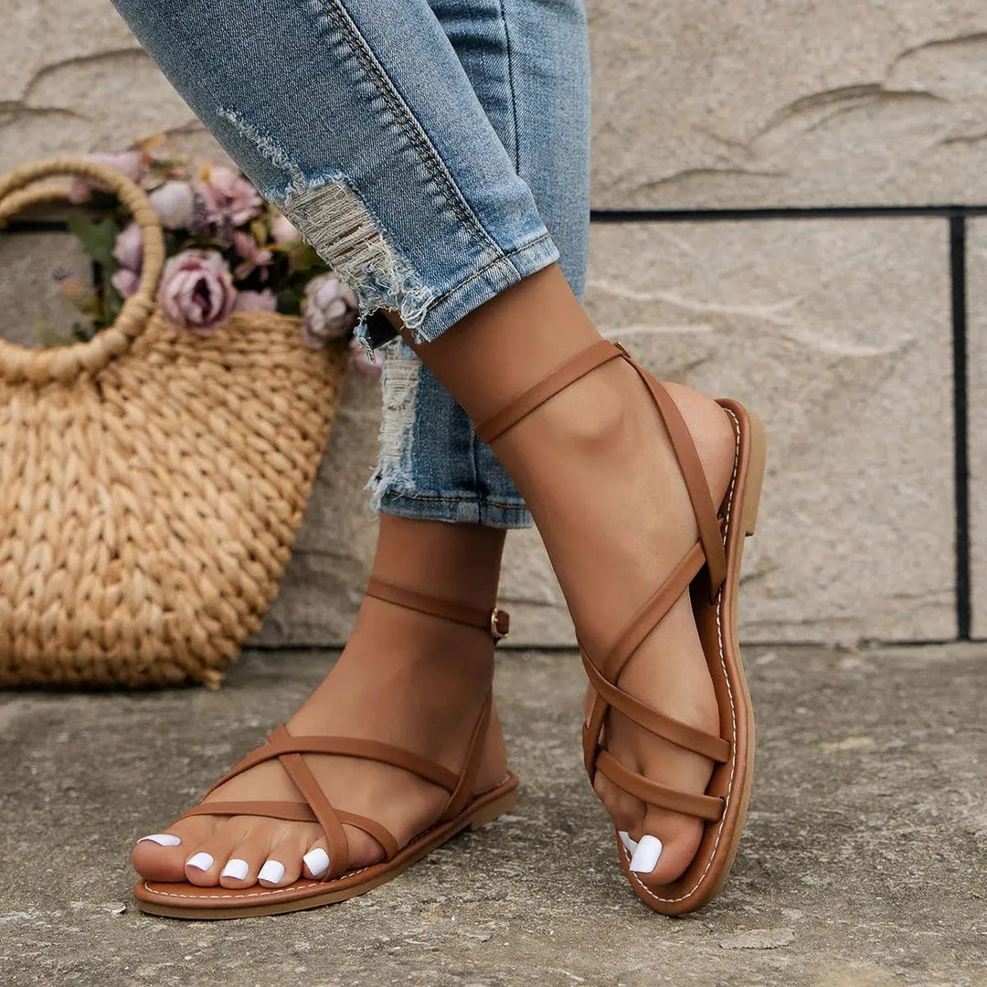 Chic women's flat sandals with a sleek open-toe and decorative criss-cross ankle straps for warm weather style.