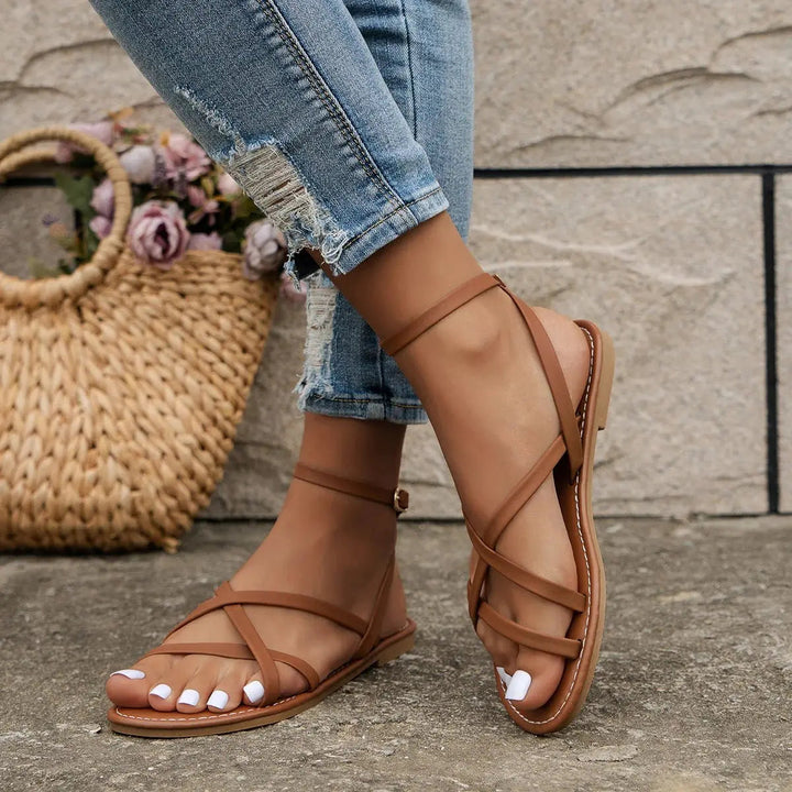 Chic women's flat sandals with a sleek open-toe and decorative criss-cross ankle straps for warm weather style.