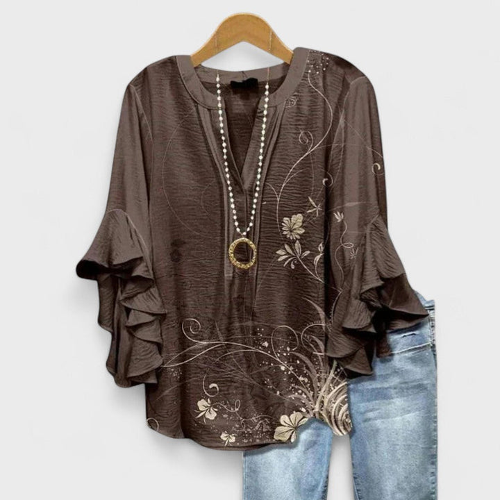 Women's casual floral print blouse. Soft, flowy fabric with ruffle accents, v-neck, and elegant flare sleeves.
