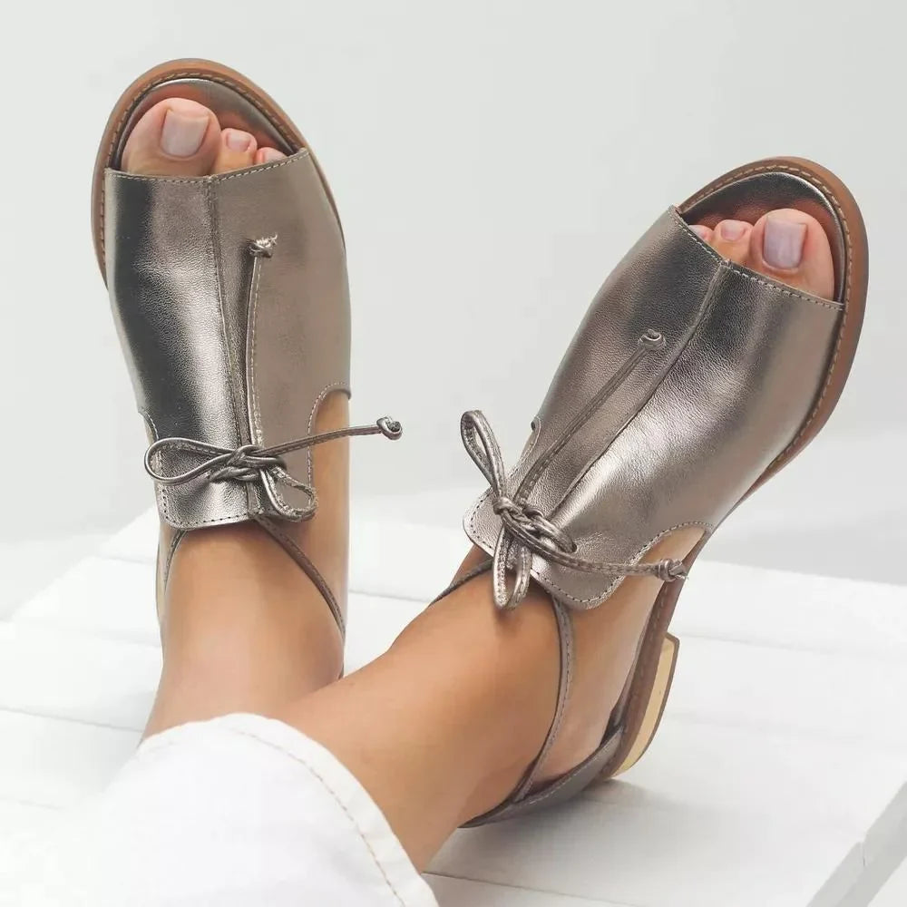 Women's gold metallic flat sandals with open toe, elegant bow tie, and adjustable ankle strap for summer.