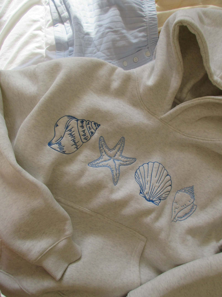 Comfortable women's grey seashell print hoodie, casual pullover with a relaxed fit & drawstring, perfect for coastal wear.