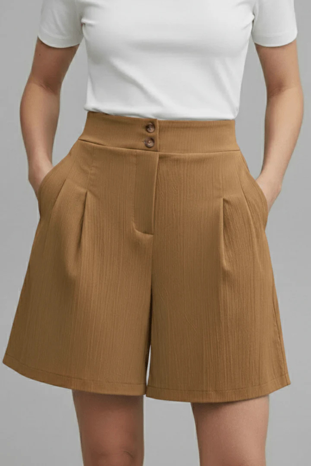 Close-up of women's high waist pleated Bermuda shorts, highlighting tailored fabric and button details.