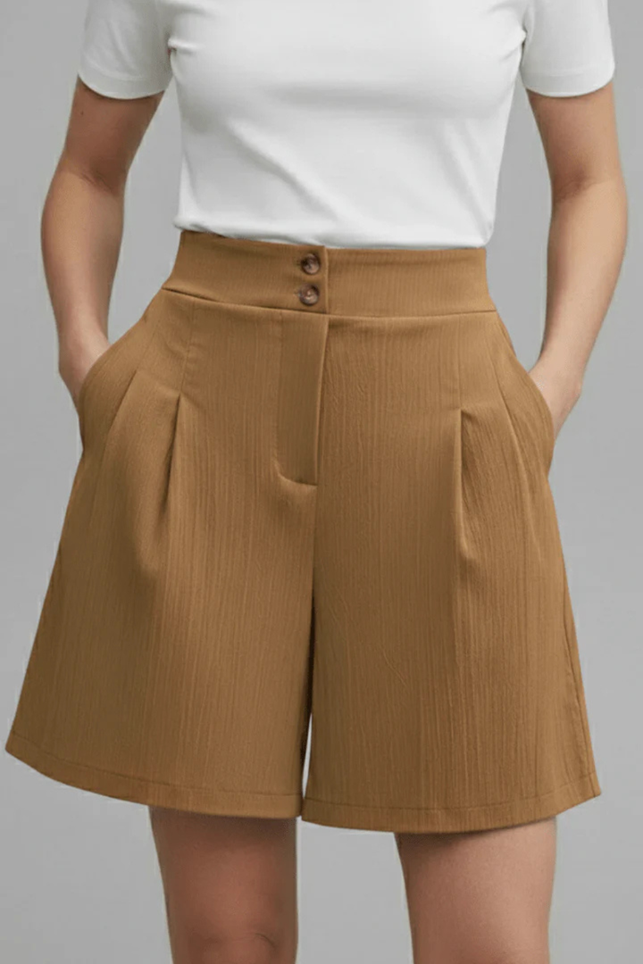 Close-up of women's high waist pleated Bermuda shorts, highlighting tailored fabric and button details.