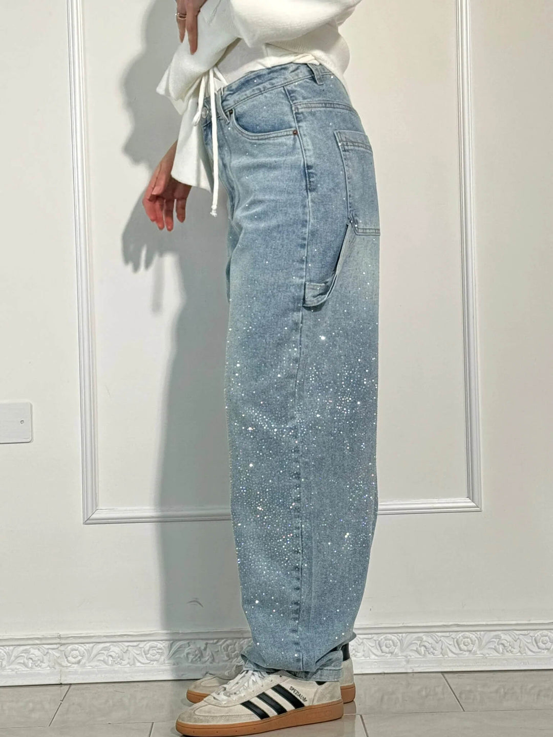 Close-up of crystal details on women's vintage denim high-waist straight leg jeans for elegant sparkle.