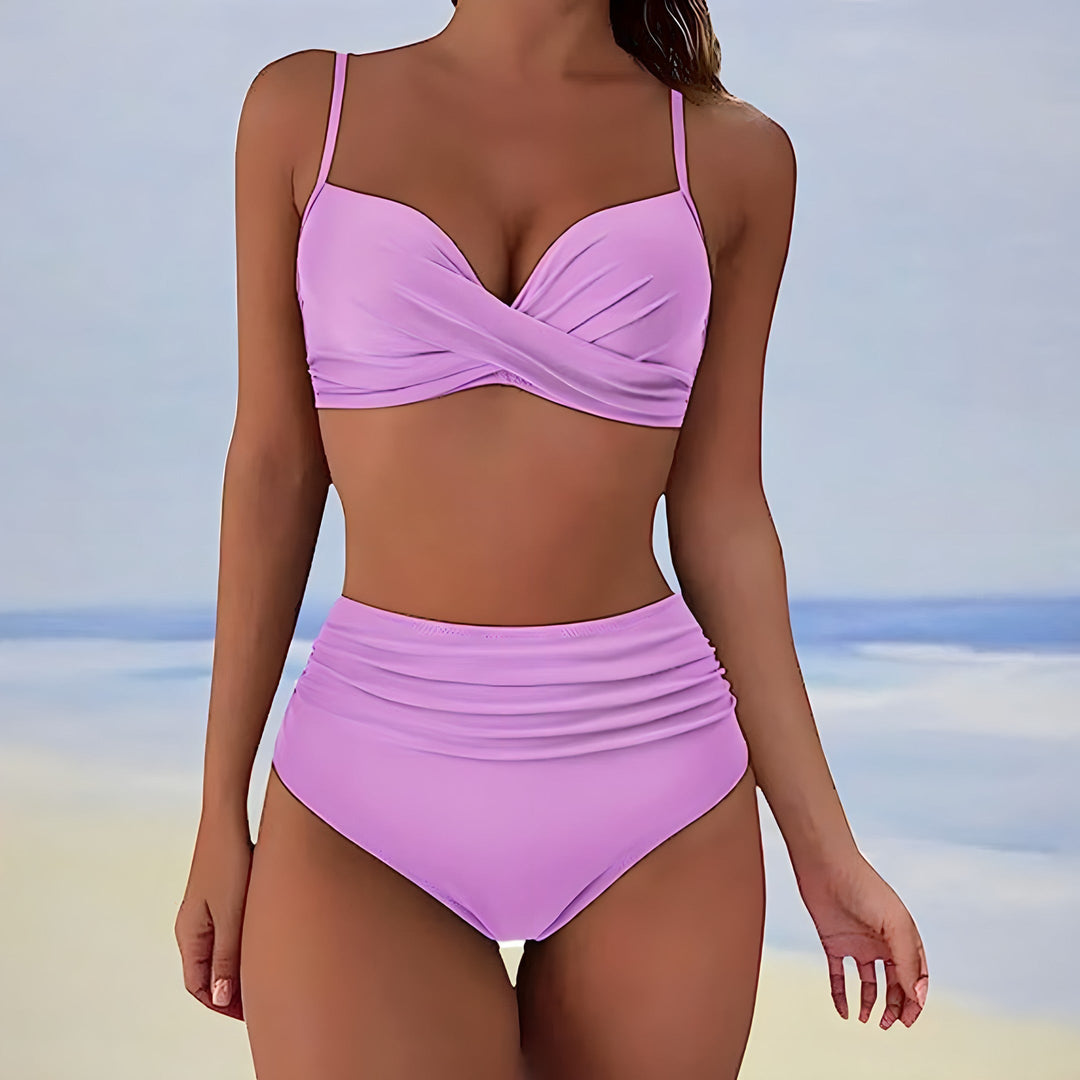 Model wearing a women's high waisted twist front bikini set on a beach, ready for summer swimwear & vacation.