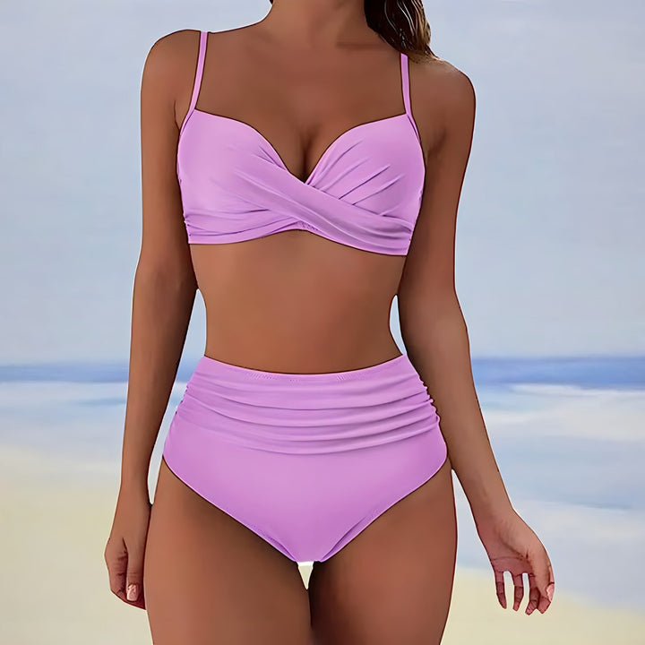 Model wearing a women's high waisted twist front bikini set on a beach, ready for summer swimwear & vacation.