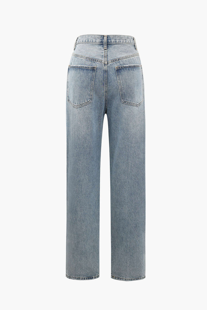 Close-up of trendy women's grey asymmetric high-waist jeans, highlighting unique button & straight leg design.