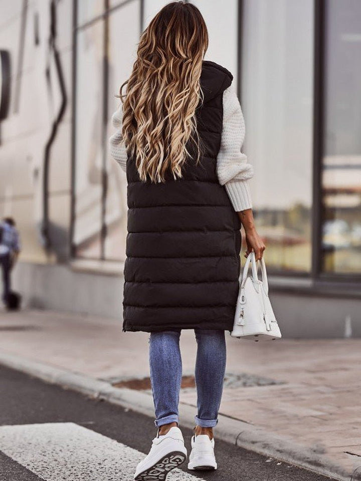 Women's long puffer vest with hood. Cozy quilted sleeveless jacket for winter & fall layering. Stay stylishly warm.