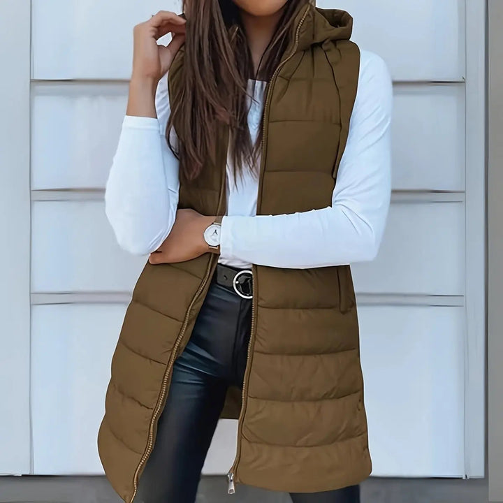 Stylish women's longline hooded puffer vest worn by model, perfect lightweight layering for cool weather.