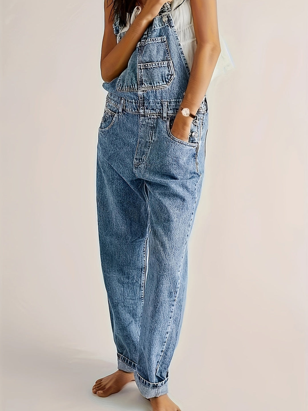 Light blue women's denim dungarees, loose fit casual overall. Adjustable straps ensure comfort and style.