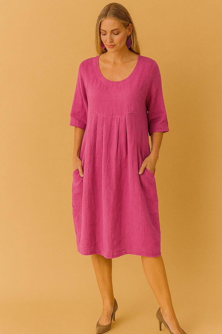 Woman wearing a stylish knee-length loose fit t-shirt dress. Features a round neck, short sleeves, and practical pockets.