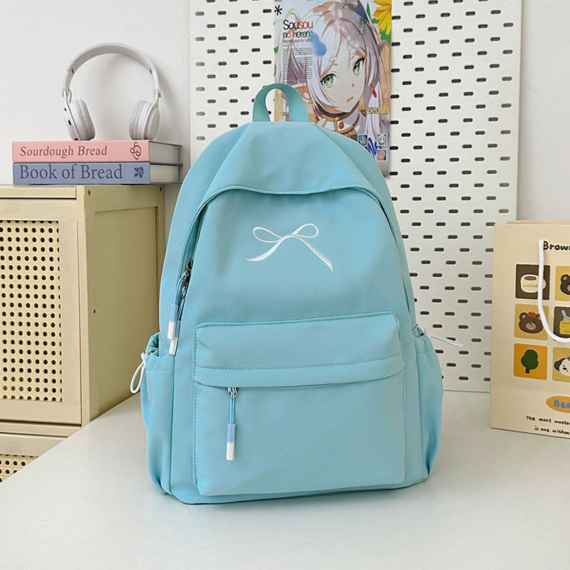 Stylish women's minimalist school backpack featuring a delicate bow embellishment. Ideal for students.