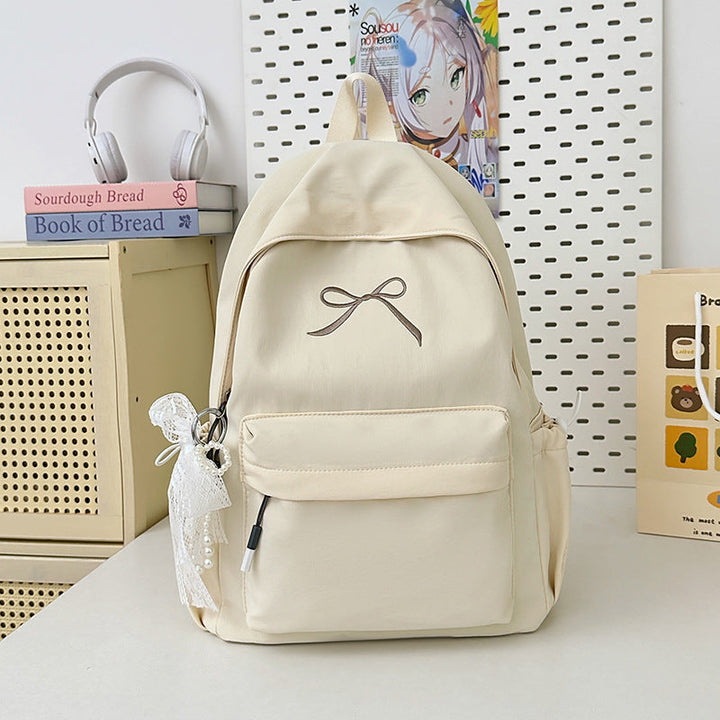 Women's minimalist school backpack with a charming bow detail. A chic and lightweight fashion accessory.
