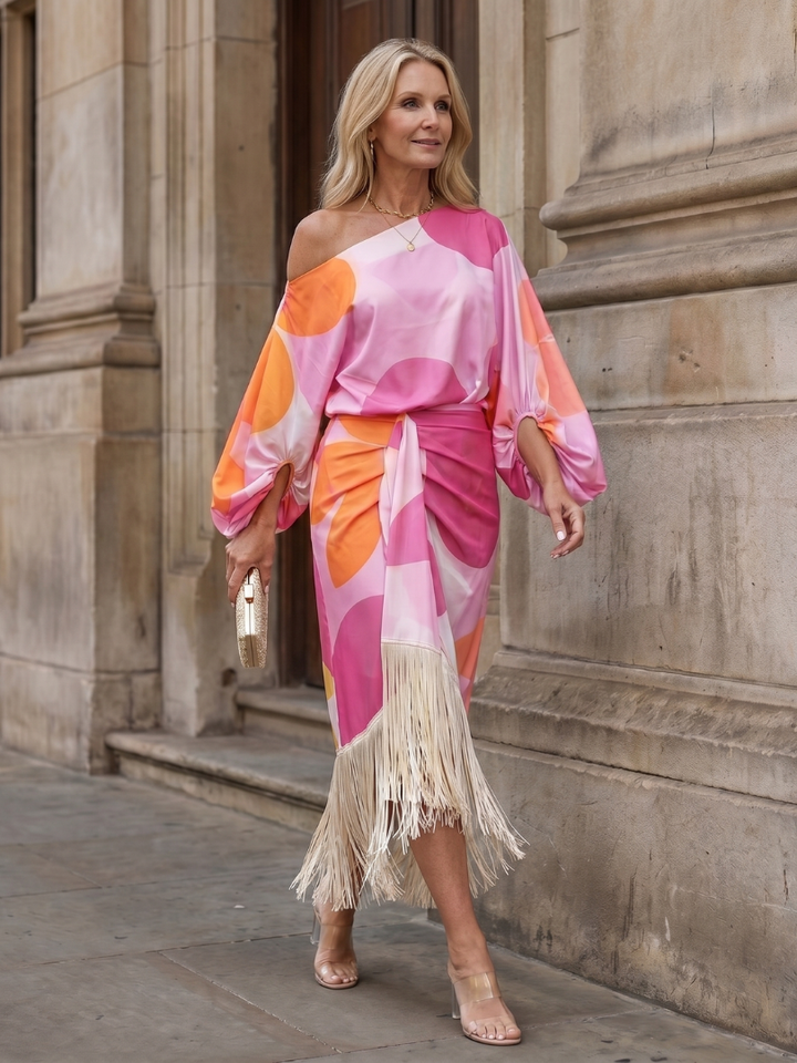 Woman models a flowy off-shoulder abstract print midi dress with stylish fringe. Perfect women's summer party dress.