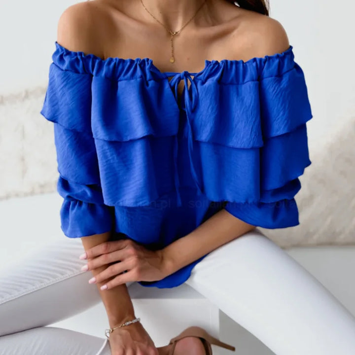 Close-up of a women's off-shoulder ruffle blouse, showing tiered detail, long sleeves, and tie-front.