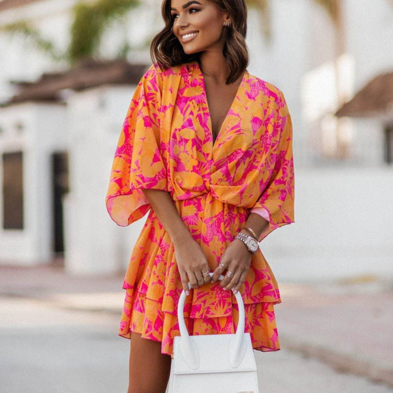 Women's orange floral mini summer dress with ruffle hem, v-neck, and batwing sleeves for a boho casual look.