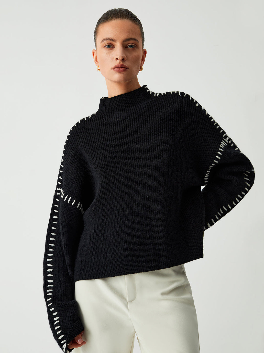 Women's oversized black sweater with modern contrast stitching and a cozy mock neck for chic casual winter fashion.