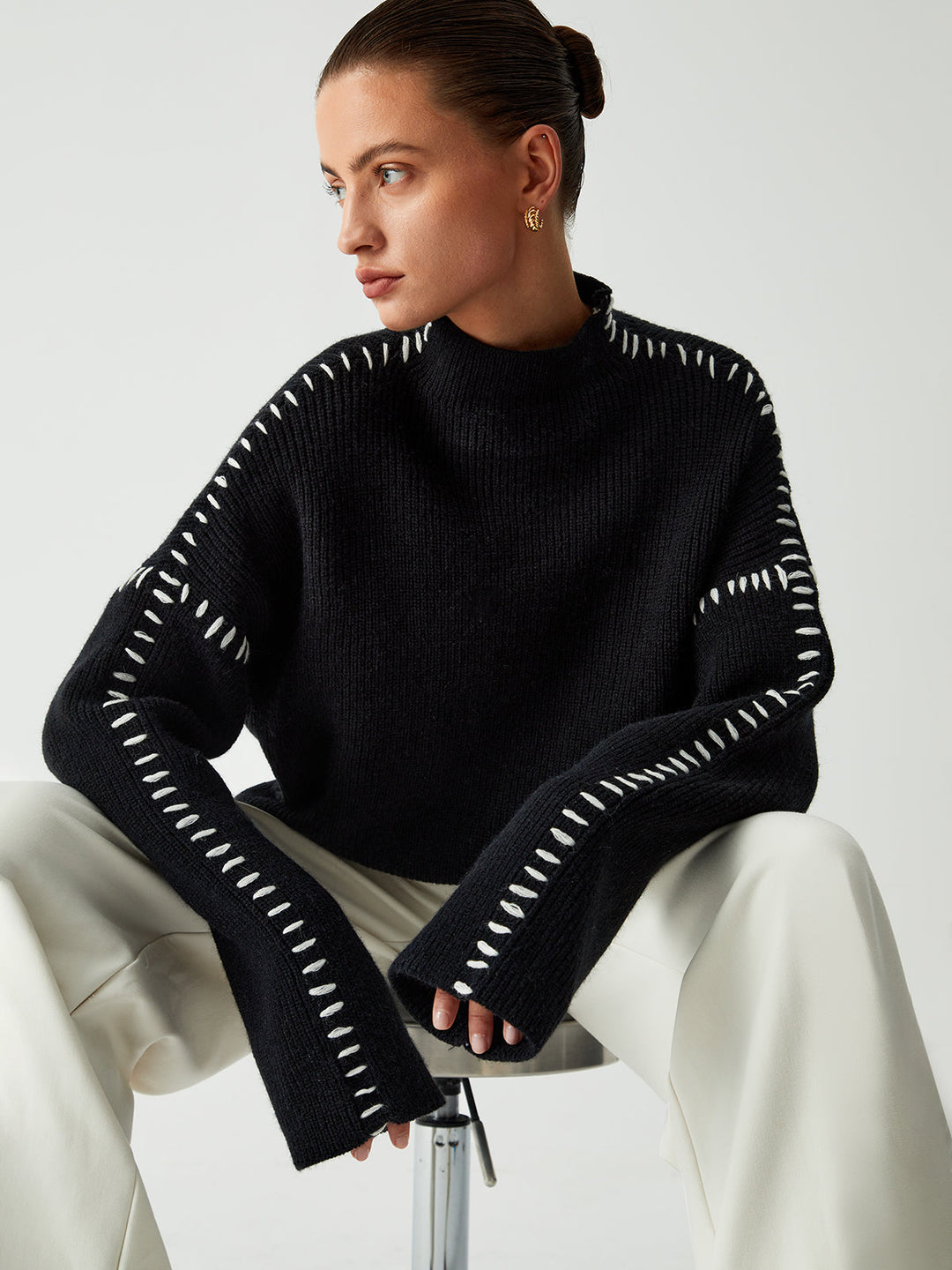 Modern black oversized sweater for women featuring unique contrast stitching and a comfortable mock neck, ideal for fall/winter.