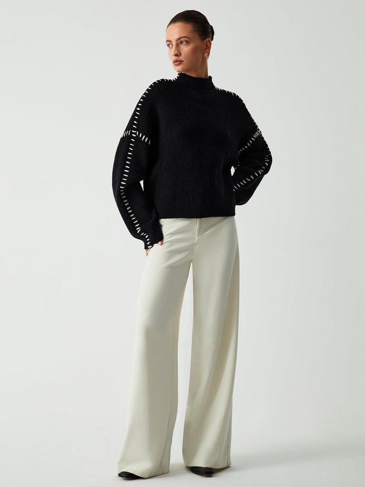 Contemporary women's black oversized sweater with eye-catching contrast stitches, a relaxed fit & warm mock neck for chic style.