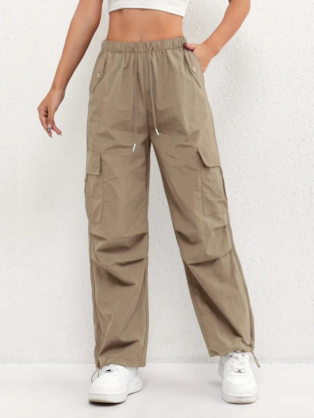 Woman models chic women's parachute cargo trousers with drawstring waist, ideal for a modern streetwear look.