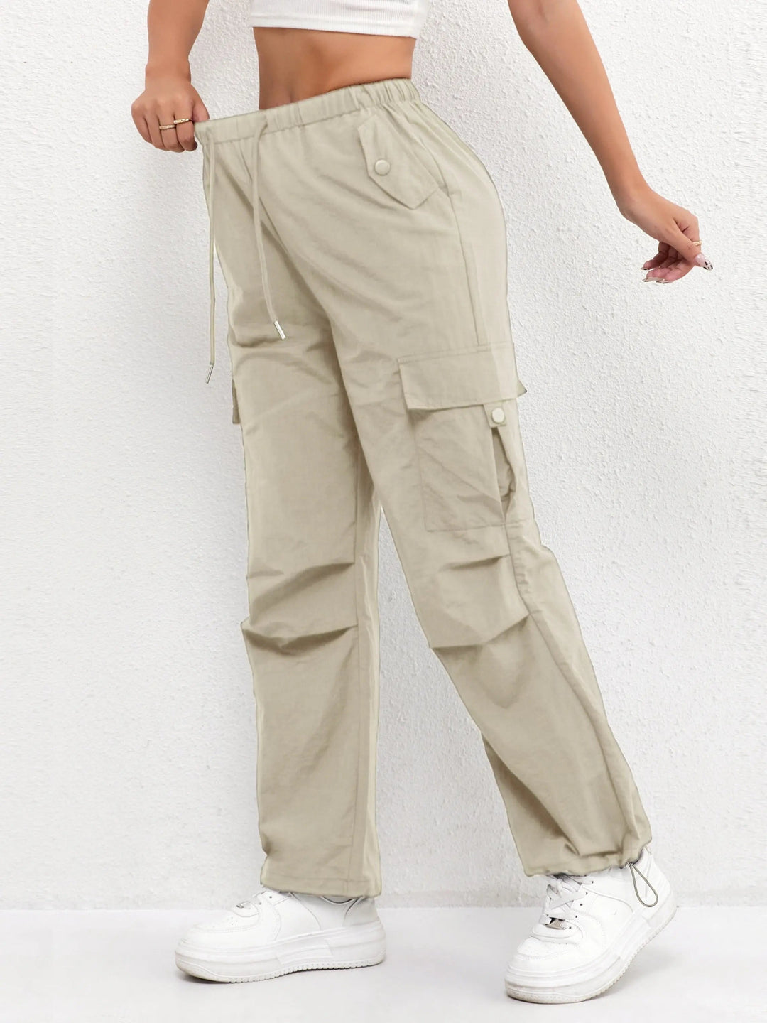Close-up of women's parachute cargo trousers, highlighting drawstring waist, utility pockets & fabric detail.