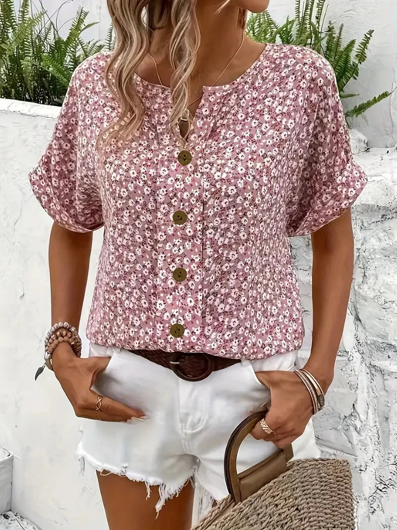 Vibrant pink floral women's blouse with cuffed short sleeves. A fashionable V-neck top for elegant or casual wear.