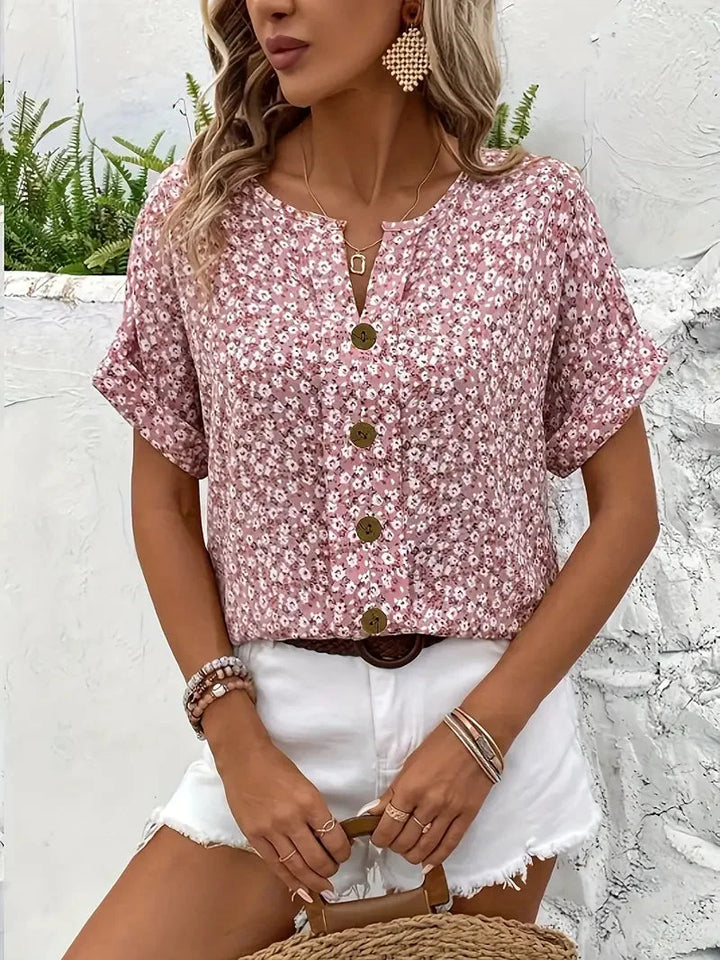 Comfortable pink floral women's top. Features a V-neck, short cuffed sleeves, and stylish button accents.