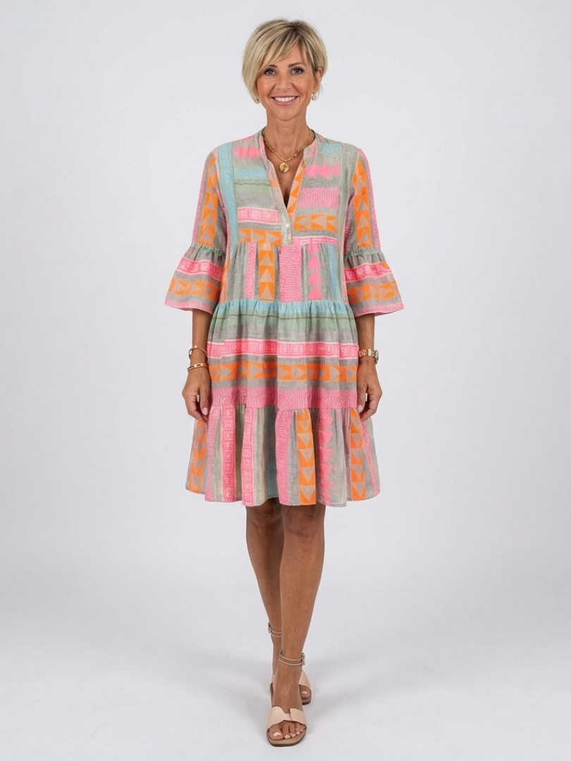Women's pink geometric print V-neck tiered knee-length dress. Perfect casual summer daywear with a relaxed fit.