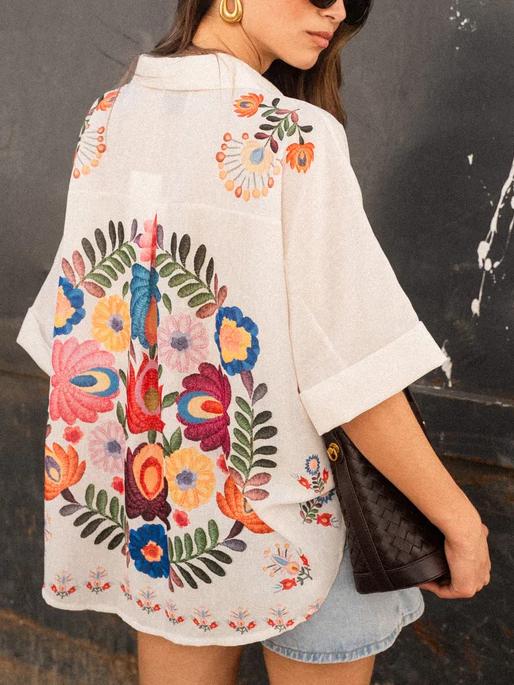 Close-up of women's short-sleeve printed collared blouse, showcasing unique fabric pattern & button details.