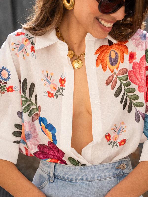 Detail of the collared neckline and button-front closure on a women's short-sleeve printed casual blouse.