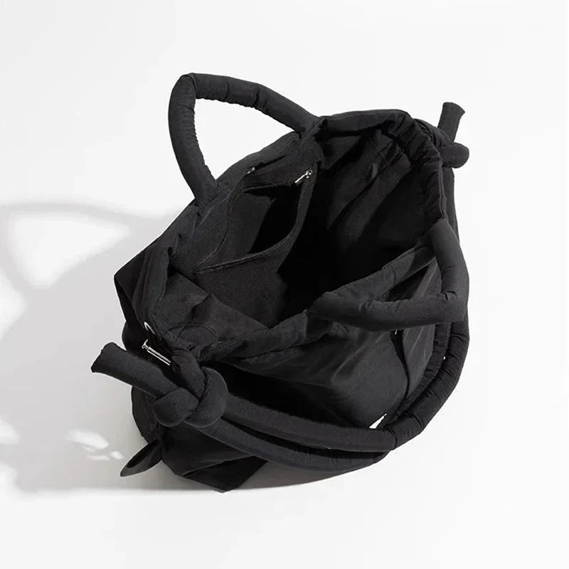 Front view of a women's quilted puffer tote bag, showcasing drawstring sides & trendy knot-detail strap.