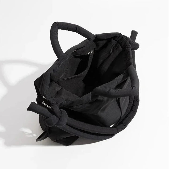 Front view of a women's quilted puffer tote bag, showcasing drawstring sides & trendy knot-detail strap.