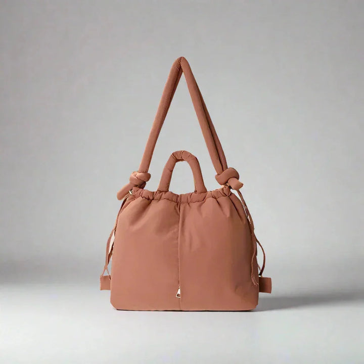 Side view of the women's puffer tote bag, highlighting the adjustable drawstring sides & quilted texture.