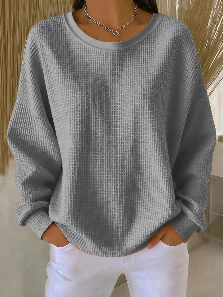 Textured waffle knit women's sweater with a relaxed fit and long sleeves, perfect for layering.