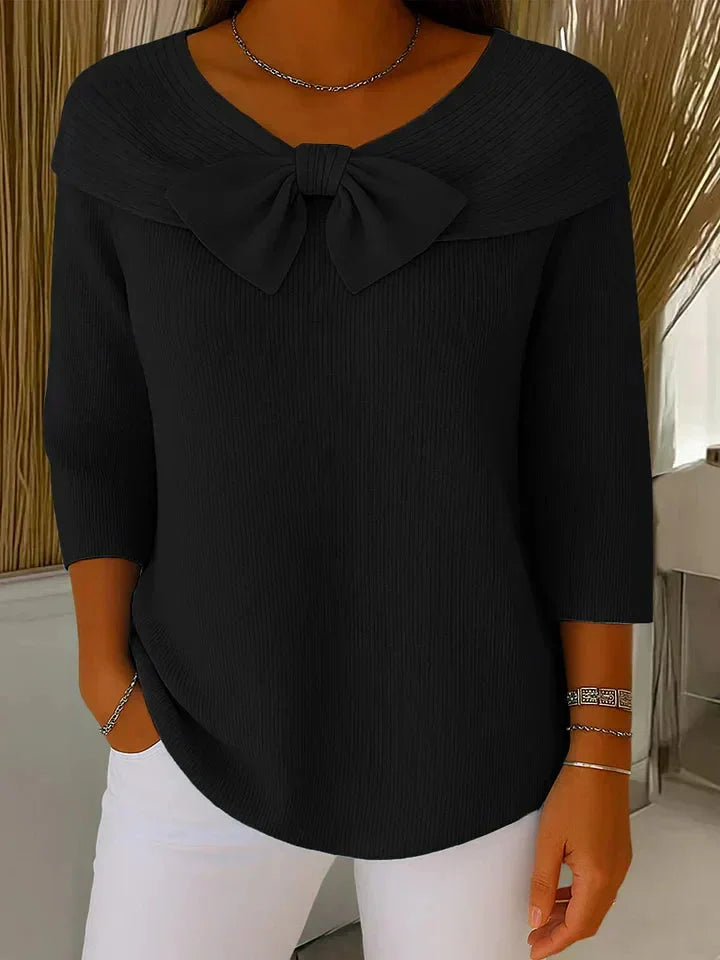 Close-up of a women's 3/4 sleeve ribbed sweater, highlighting the delicate bow detail at the V-neck.