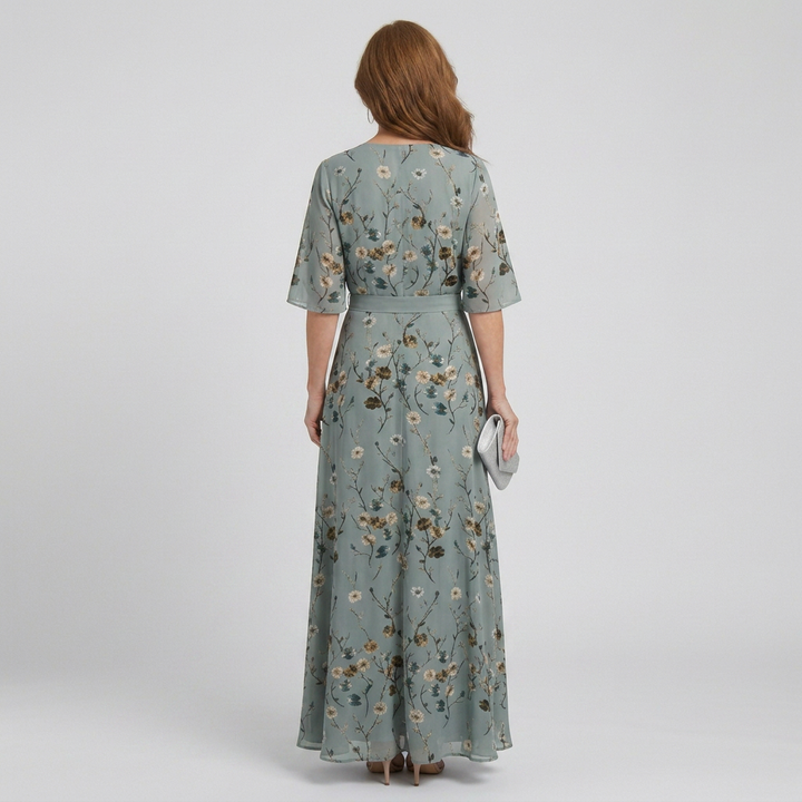 View of a women's flowy sage green floral halter maxi dress, a comfortable and chic sleeveless summer vacation dress.