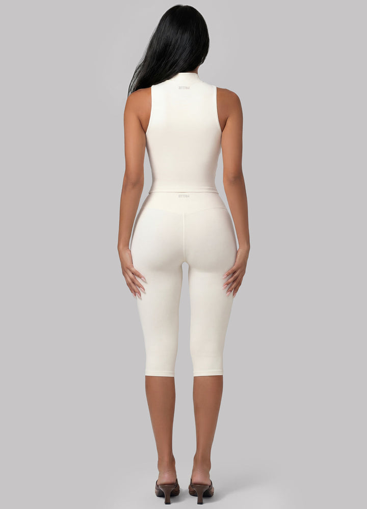Model in ivory sculpting capri leggings performing Pilates. High-waisted activewear for studio and workout.